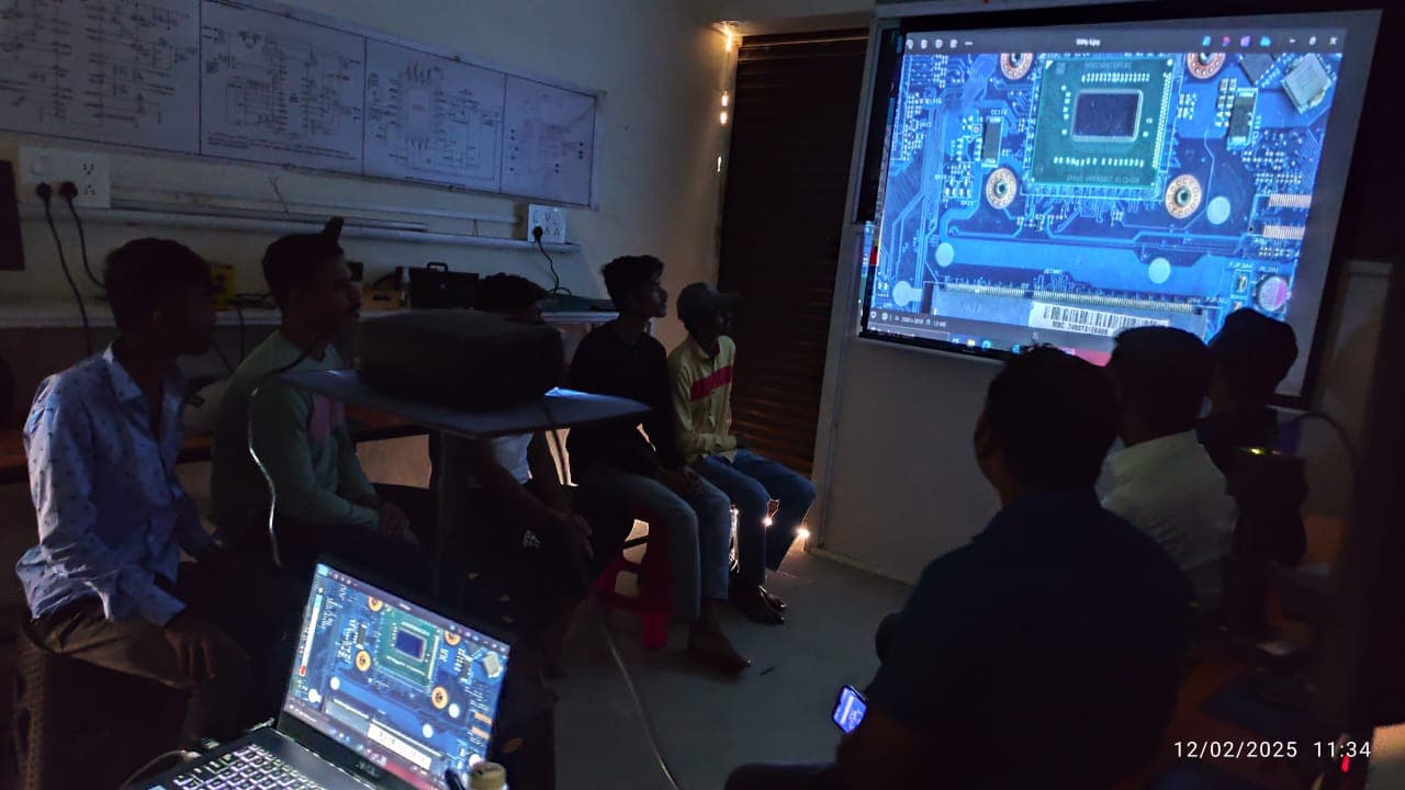 Students in a Laptian classroom reviewing laptop motherboard schematics on a projector screen