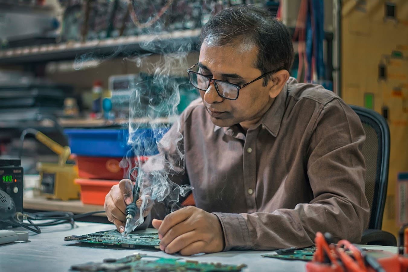 Laptian instructor performing precision soldering on a circuit board in the training lab