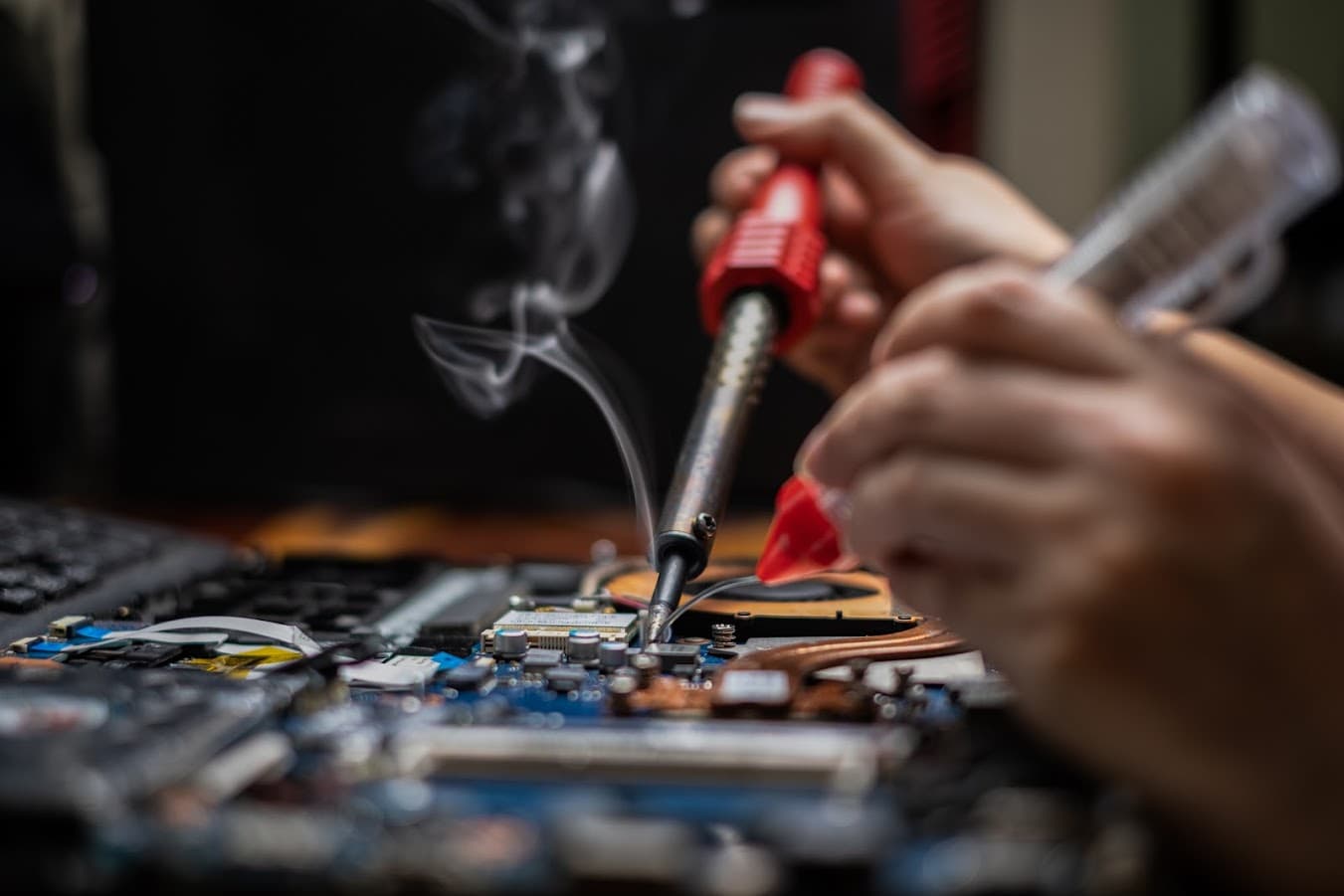 Close-up of chip-level soldering on a laptop motherboard during hands-on repair training