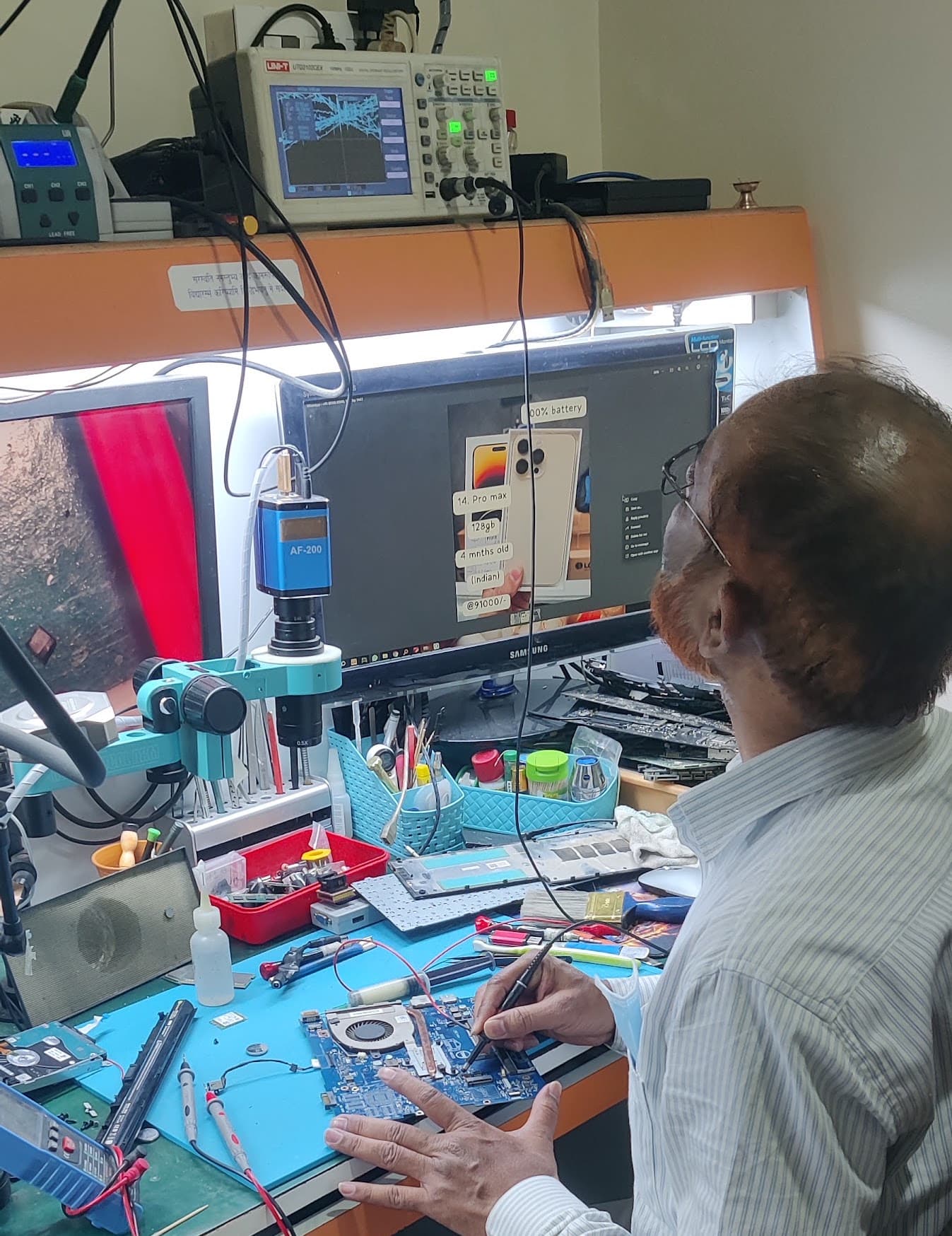 Senior technician diagnosing a laptop motherboard at a fully equipped Laptian repair lab